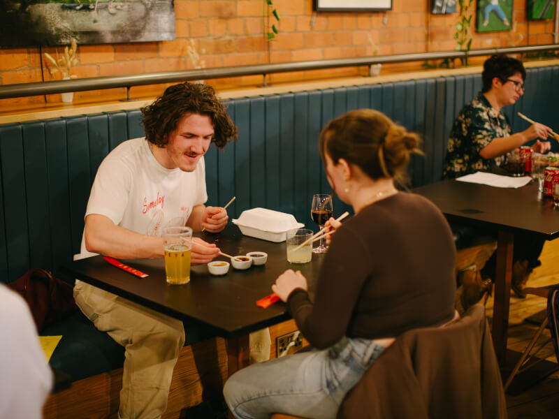 People sitting down at a table eating dumplings